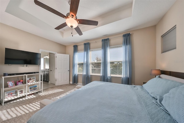 carpeted bedroom featuring a tray ceiling and ceiling fan