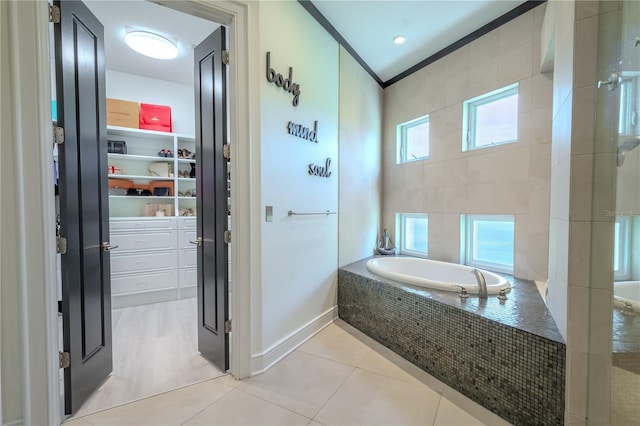 bathroom with tiled tub, crown molding, and tile patterned flooring