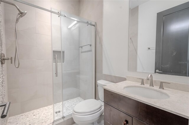 bathroom featuring vanity, a shower with shower door, and toilet