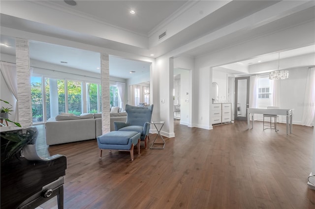 living room featuring a tray ceiling, a notable chandelier, crown molding, and dark wood-type flooring