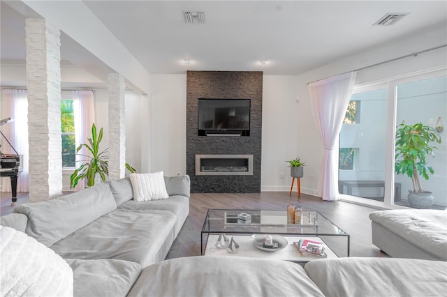 living room with decorative columns, a large fireplace, and hardwood / wood-style floors