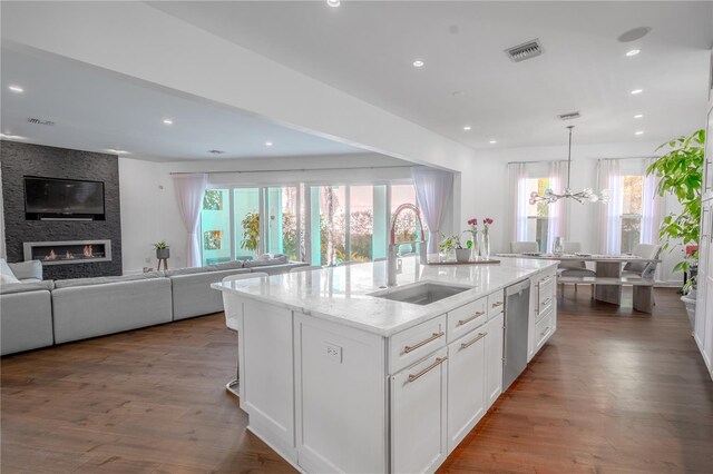 kitchen featuring sink, dishwasher, hardwood / wood-style floors, an island with sink, and white cabinets