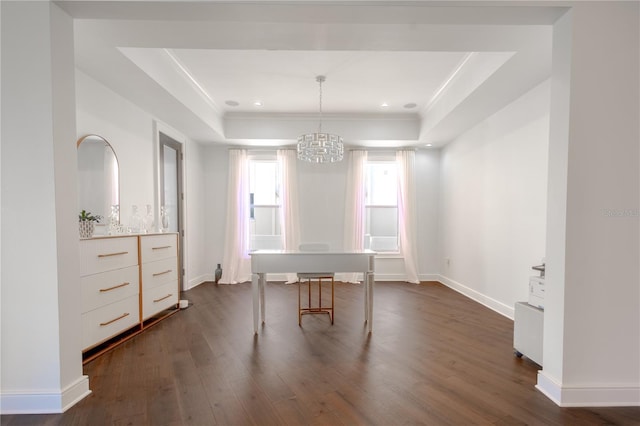 unfurnished dining area with dark wood-type flooring, an inviting chandelier, and a tray ceiling