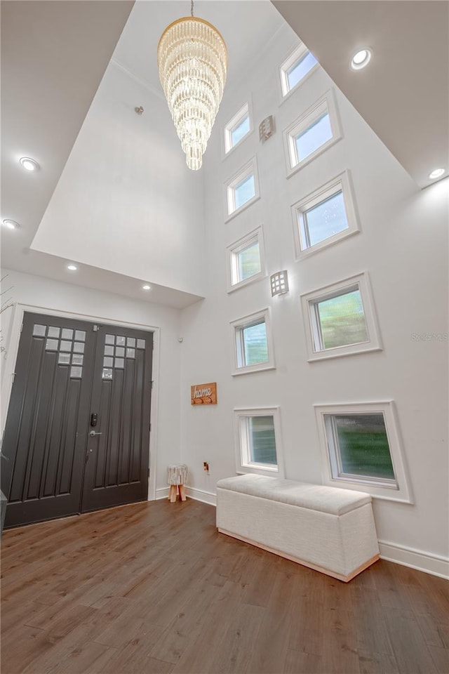 foyer with hardwood / wood-style flooring, a high ceiling, and an inviting chandelier