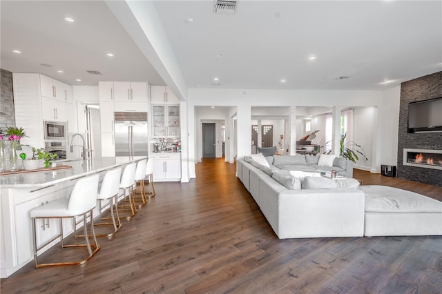 living room with a fireplace, dark hardwood / wood-style flooring, and sink