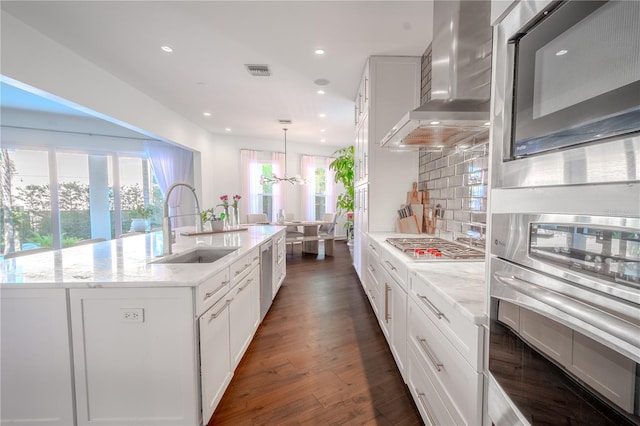 kitchen featuring white cabinetry, sink, pendant lighting, and wall chimney exhaust hood