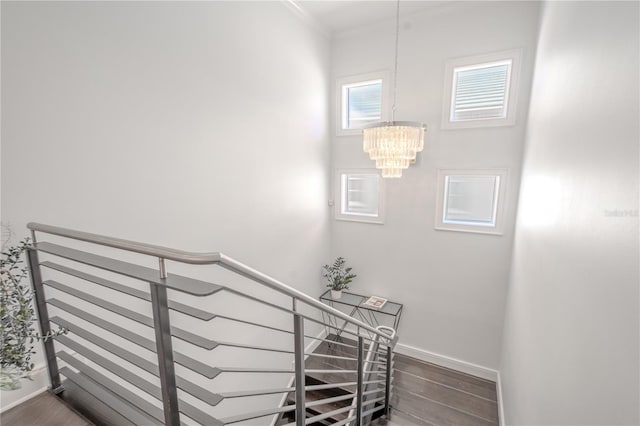 stairs with an inviting chandelier, hardwood / wood-style flooring, and ornamental molding