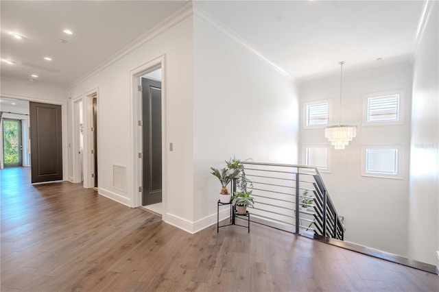 hallway featuring hardwood / wood-style floors, crown molding, and a chandelier