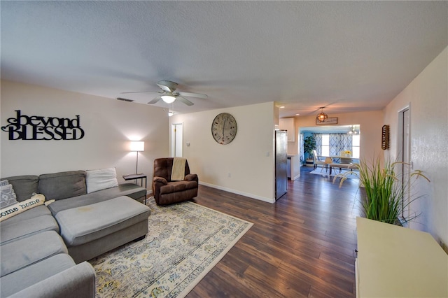 living room featuring ceiling fan, dark wood-type flooring, and a textured ceiling