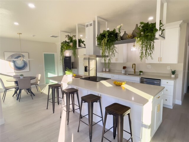 kitchen with light hardwood / wood-style flooring, white cabinetry, a kitchen island, and sink