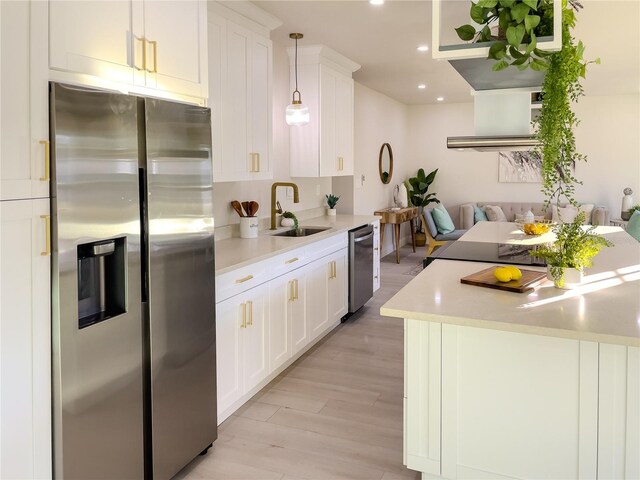 kitchen with pendant lighting, white cabinets, sink, and appliances with stainless steel finishes