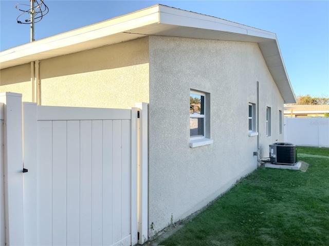 view of side of home with a lawn and central AC