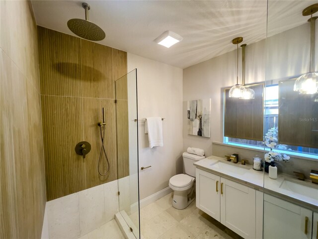 bathroom with tiled shower, vanity, and toilet