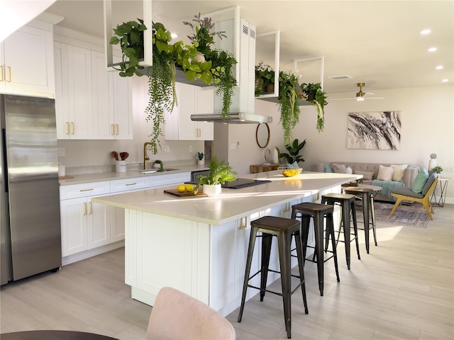 5516 Golden Dr, Tampa, FL 33634 - kitchen featuring freestanding refrigerator, a sink, light wood-style flooring, range hood, and a breakfast bar