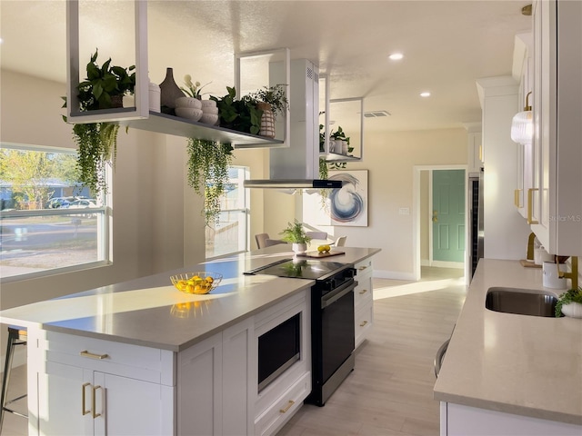 5516 Golden Dr, Tampa, FL 33634 - kitchen featuring black electric range oven, white cabinetry, light countertops, light wood-style flooring, and recessed lighting