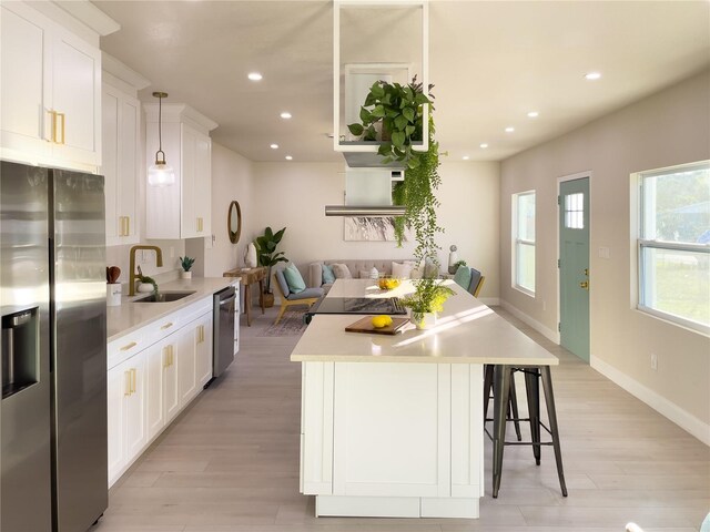 kitchen featuring appliances with stainless steel finishes, decorative light fixtures, white cabinetry, and sink