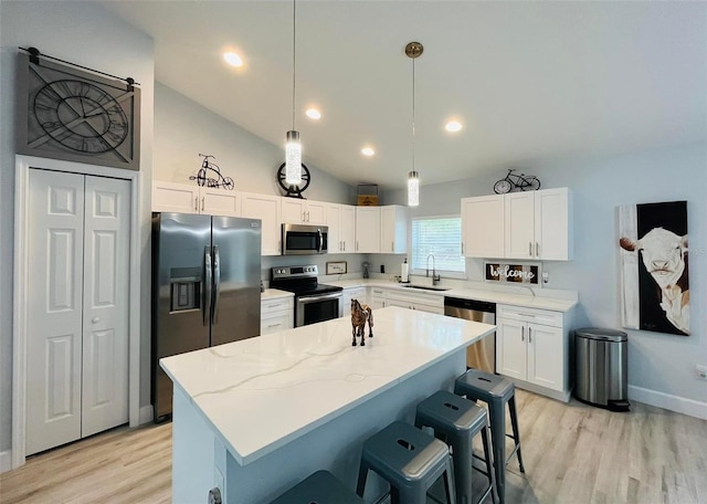 kitchen featuring stainless steel appliances, a center island, white cabinetry, hanging light fixtures, and lofted ceiling