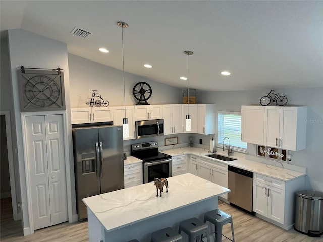 kitchen featuring sink, hanging light fixtures, vaulted ceiling, white cabinets, and appliances with stainless steel finishes