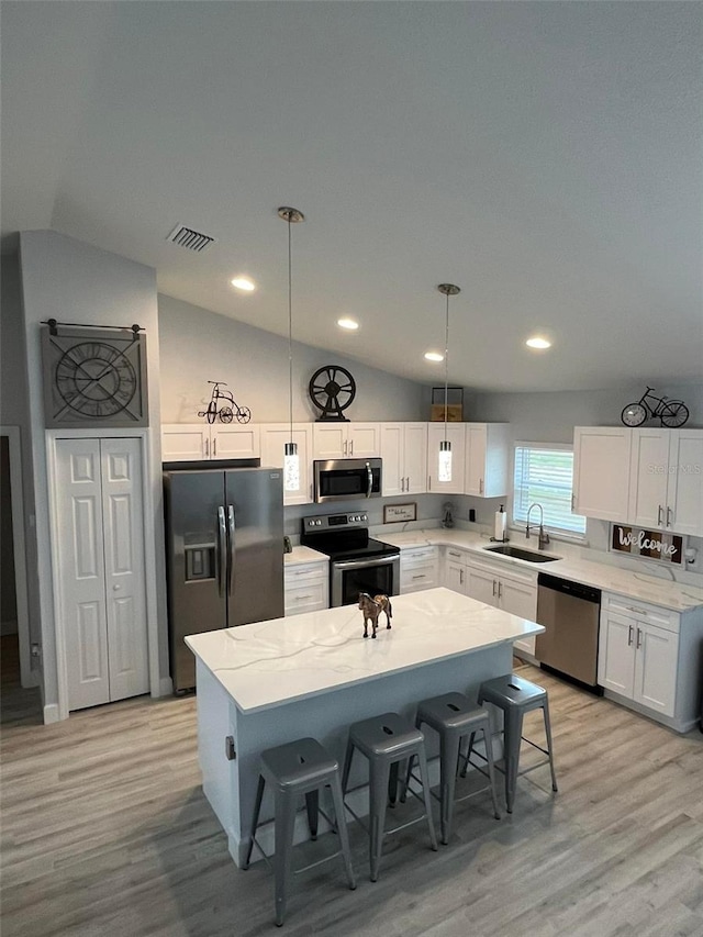 kitchen featuring pendant lighting, stainless steel appliances, vaulted ceiling, and sink