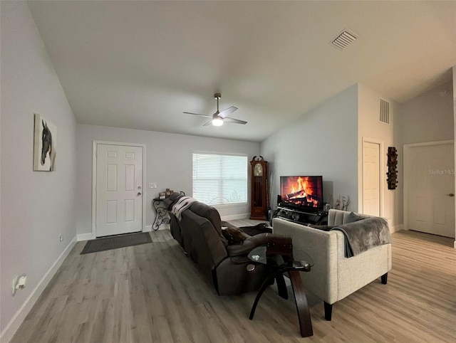 living room featuring ceiling fan, light hardwood / wood-style floors, and vaulted ceiling