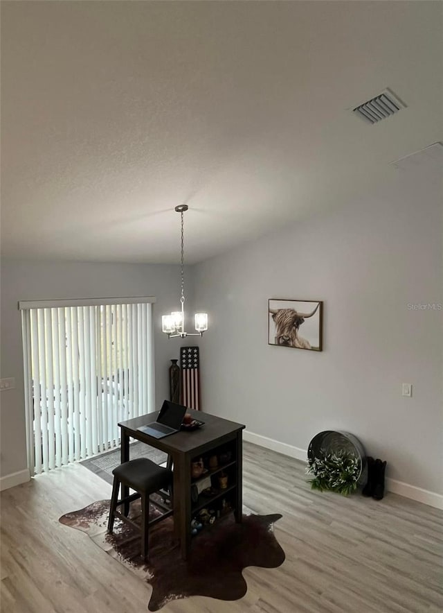 dining space with light hardwood / wood-style floors, vaulted ceiling, and a chandelier