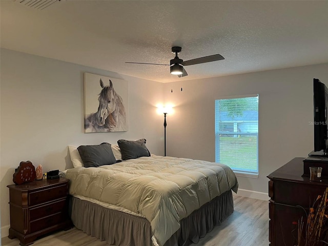 bedroom featuring a textured ceiling, light wood-type flooring, and ceiling fan