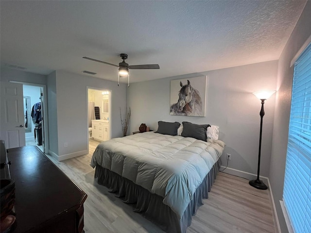 bedroom featuring a walk in closet, light hardwood / wood-style floors, a closet, and ceiling fan