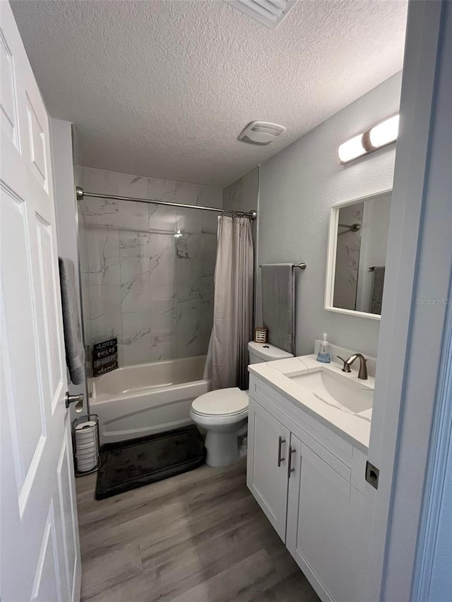 full bathroom with hardwood / wood-style flooring, vanity, shower / bath combo with shower curtain, and a textured ceiling