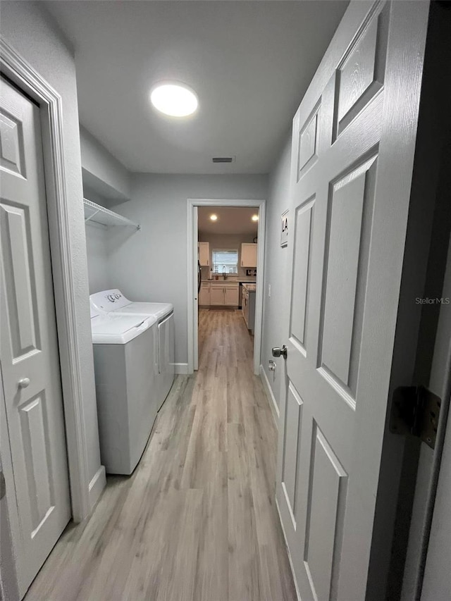 laundry area with washer and dryer and light wood-type flooring