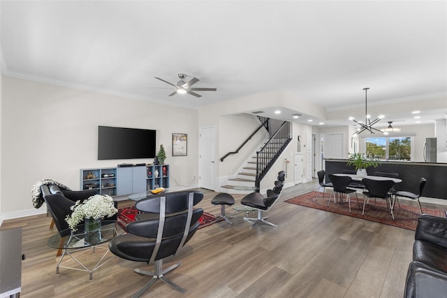 living room featuring hardwood / wood-style flooring, ceiling fan with notable chandelier, and ornamental molding