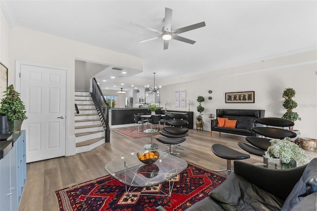 living room featuring crown molding, ceiling fan with notable chandelier, and hardwood / wood-style flooring