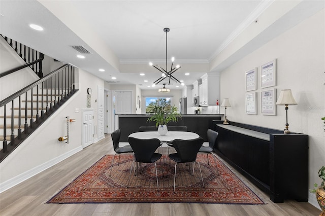 dining space with an inviting chandelier, ornamental molding, and light wood-type flooring