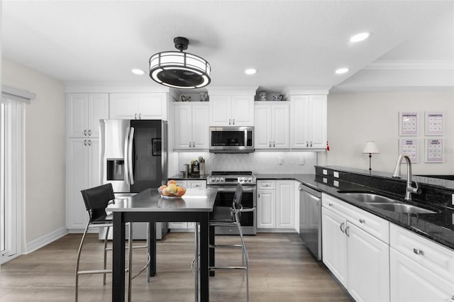 kitchen with hardwood / wood-style floors, white cabinetry, sink, and stainless steel appliances