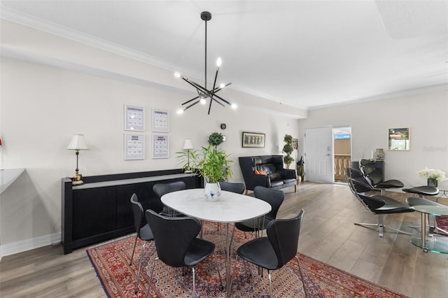 dining area with hardwood / wood-style floors, an inviting chandelier, and ornamental molding