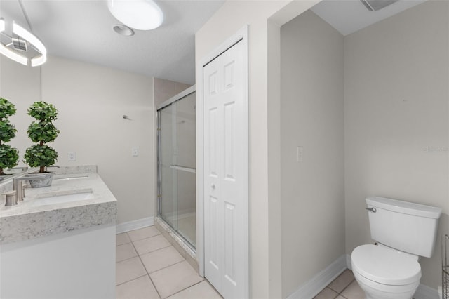 bathroom with tile patterned flooring, vanity, a shower with door, and toilet