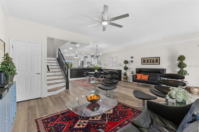 living room with stairway, wood finished floors, ceiling fan, a chandelier, and recessed lighting