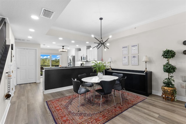 dining space with crown molding, a chandelier, light wood-style flooring, baseboards, and recessed lighting
