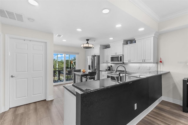 kitchen featuring appliances with stainless steel finishes, crown molding, recessed lighting, decorative backsplash, and white cabinetry