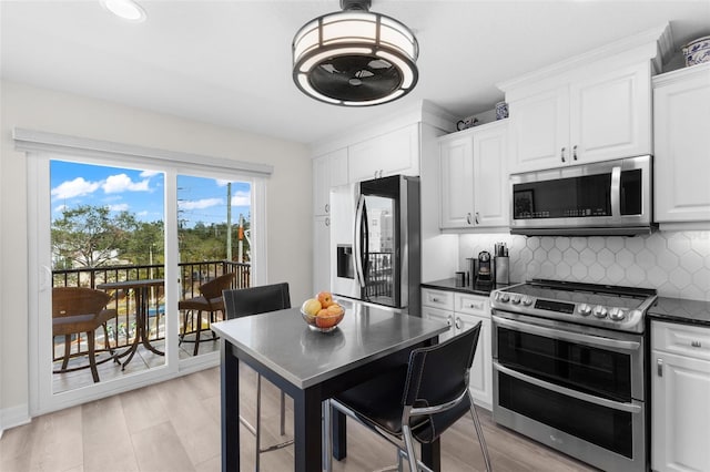 kitchen with stainless steel appliances, dark countertops, white cabinetry, backsplash, and recessed lighting