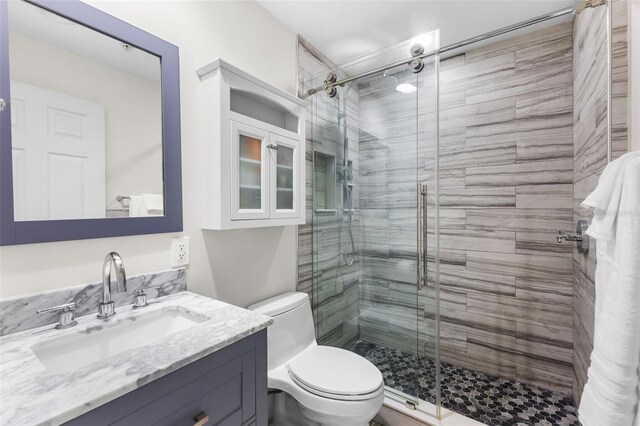 full bathroom with a shower stall, toilet, and vanity