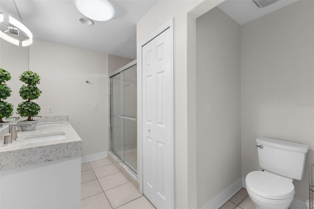full bath featuring a stall shower, tile patterned floors, toilet, baseboards, and double vanity
