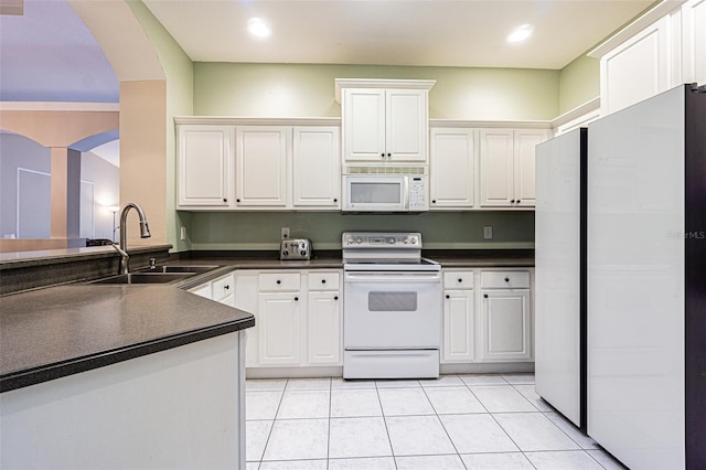 kitchen featuring white cabinets, white appliances, light tile patterned flooring, and sink