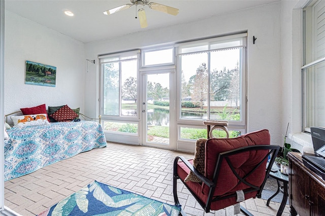 bedroom featuring access to outside, ceiling fan, and a water view