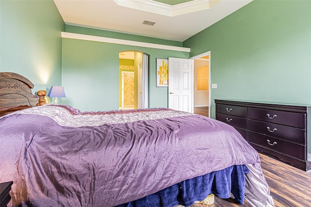 bedroom featuring hardwood / wood-style flooring, a raised ceiling, and crown molding