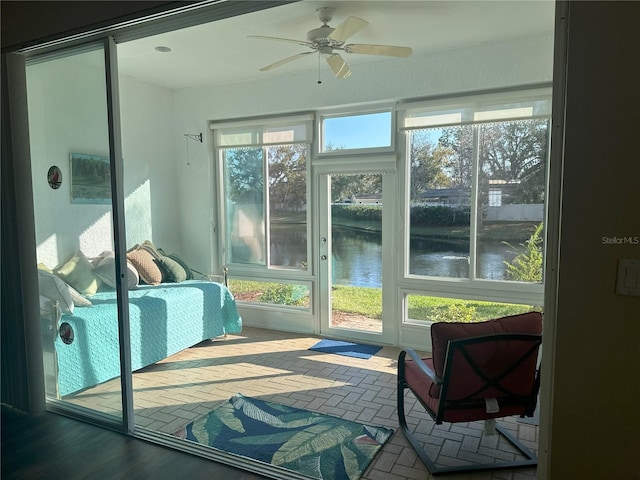 sunroom with a water view and ceiling fan