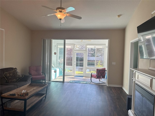 living room featuring ceiling fan, dark hardwood / wood-style flooring, and a textured ceiling