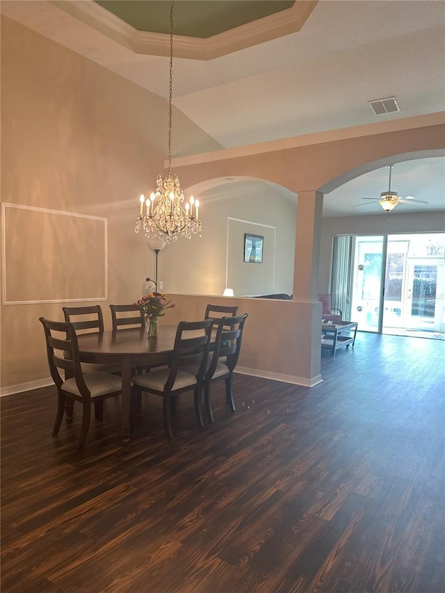 dining room with a tray ceiling, ceiling fan with notable chandelier, and dark hardwood / wood-style floors