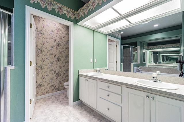 bathroom with tile patterned flooring, vanity, a shower with shower door, and toilet