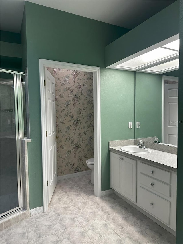 bathroom featuring a shower with door, a skylight, vanity, tile patterned floors, and toilet