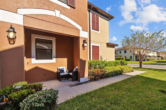 property entrance with a lawn and a patio area